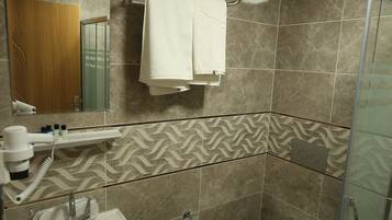 Baño con lavamanos, espejo, toallero, ducha e inodoro.