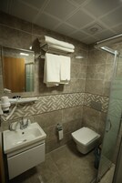 Baño con lavamanos, espejo, toallero, ducha e inodoro.