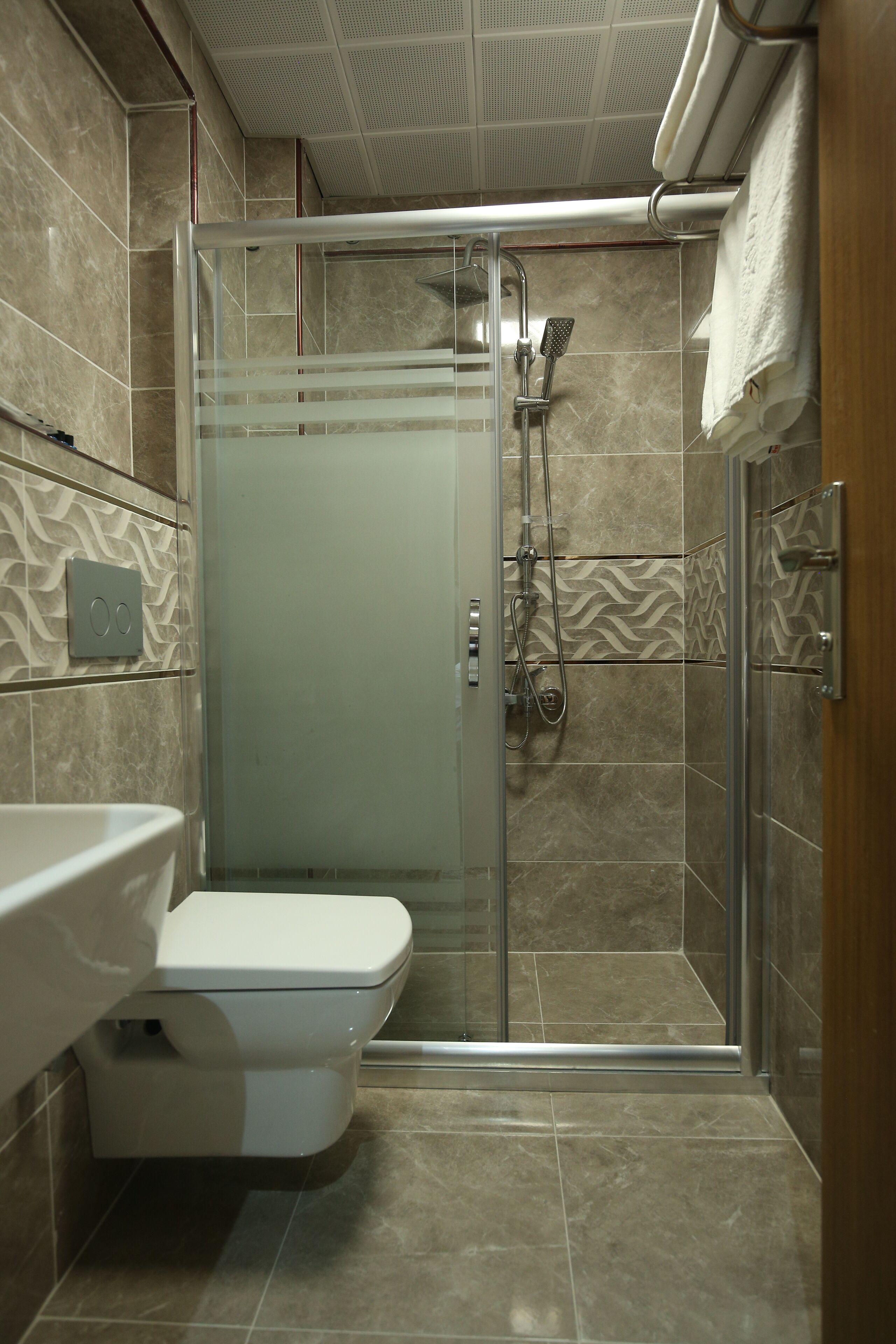 A modern bathroom with a glass-enclosed shower, a white sink, and a toilet.