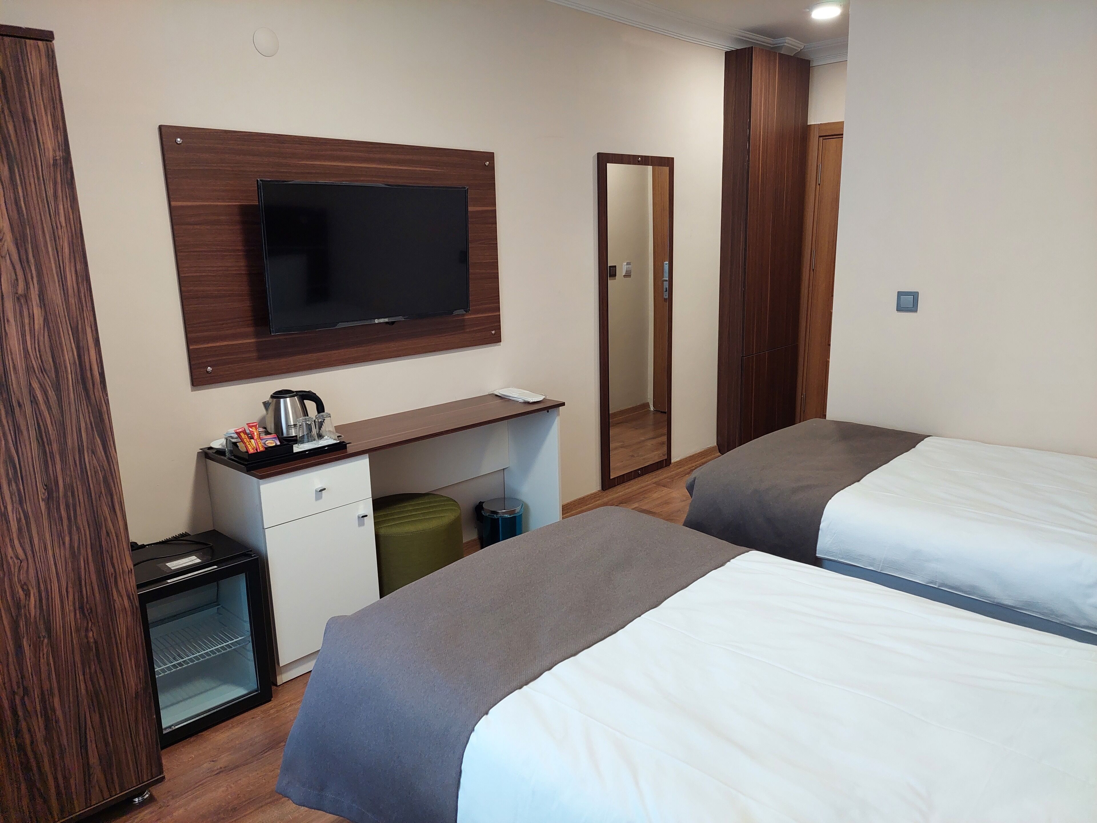 Een hotelkamer met twee bedden, een bureau, een flatscreen televisie, een minibar, een prullenbak en een kledingkast.