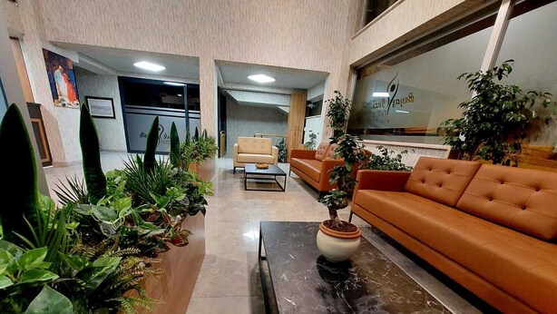 A lobby with a sofa, a coffee table, and potted plants. - Beyaz Inci Otel (Sivas)