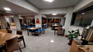 A spacious dining area with multiple tables and chairs, a coffee machine, and potted plants. - Beyaz Inci Otel (Sivas)