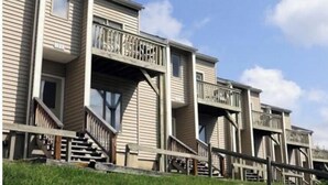 Une rangée de maisons de ville dotées de balcons, de rampes en bois et d’une pelouse devant.