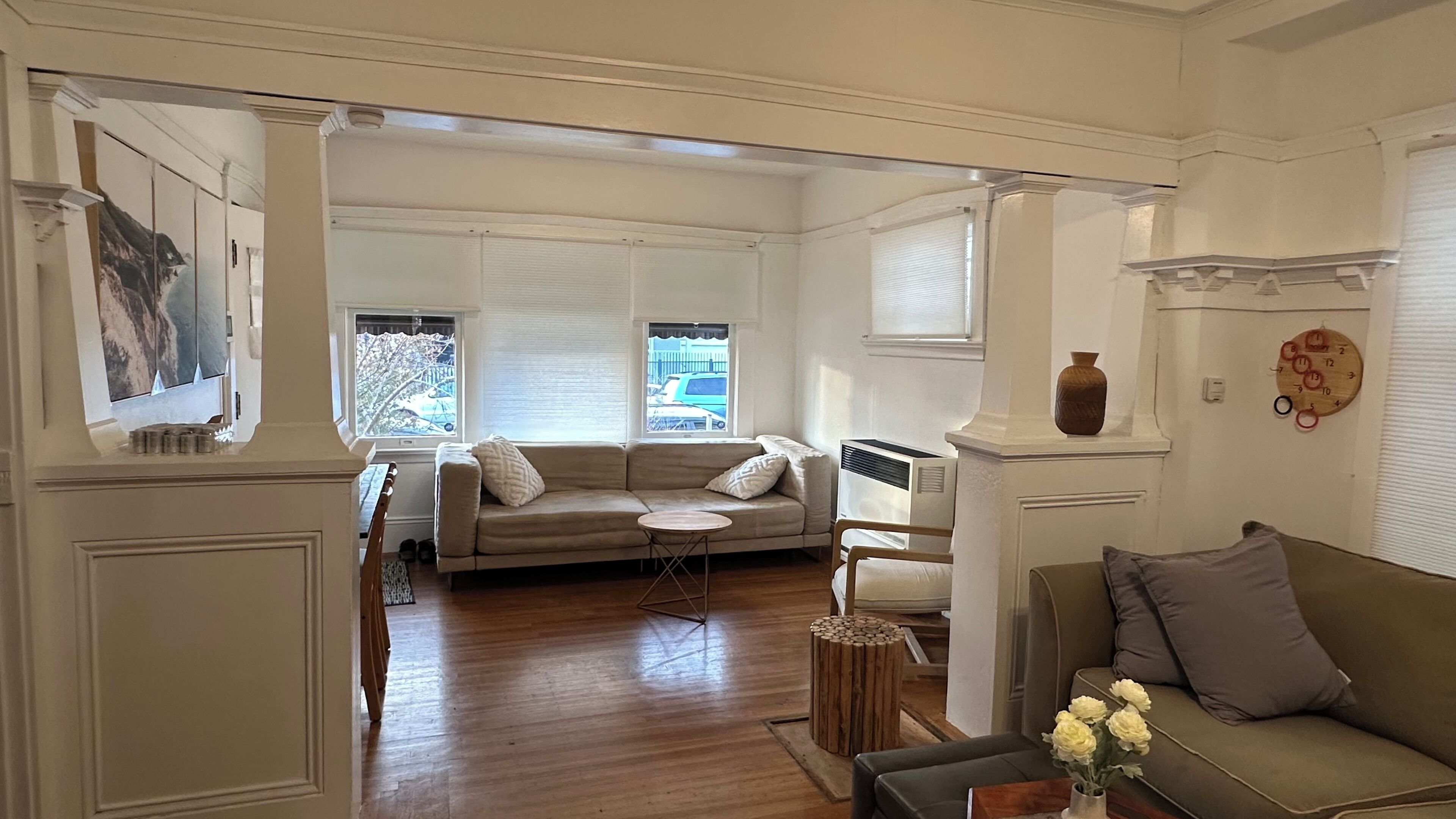 A spacious living room with a beige sofa, a round wooden coffee table, and a grey couch.