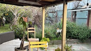 Eine Terrassengruppe im Freien mit gelben Stühlen und einem Tisch, umgeben von Kübelpflanzen und einer Holzpergola.