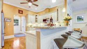 A kitchen with white cabinets, a granite countertop, and a ceiling fan. - Lakeside Retreat |Private Pool| 8min walk Downtown (Saint Augustine)