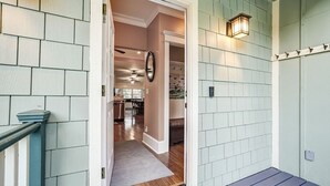 A hallway with a wooden floor, a light green wall, and a door leading to a room with a dining area. - Lakeside Retreat |Private Pool| 8min walk Downtown (Saint Augustine)