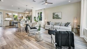 A spacious living area with a modern kitchen, a dining area, and a seating area with a sofa and chairs. - LUX Riberia – 315 | 12-min walk to Historic DTN (St. Augustine)