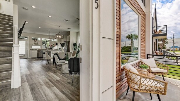 A modern interior with a staircase, a dining area, and a balcony with wicker furniture. - LUX Riberia – 315 | 12-min walk to Historic DTN (St. Augustine)
