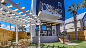 A modern two-story house with a balcony, a pergola, and a patio with wicker furniture. - LUX Riberia – 315 | 12-min walk to Historic DTN (St. Augustine)