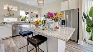 A modern kitchen with a central island, stainless steel appliances, and a large window. - LUX Riberia – 315 | 12-min walk to Historic DTN (St. Augustine)