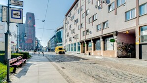 Un tram sur les rails, un banc et un bâtiment sur lequel on peut lire l’inscription « WITA STWOSZA ».