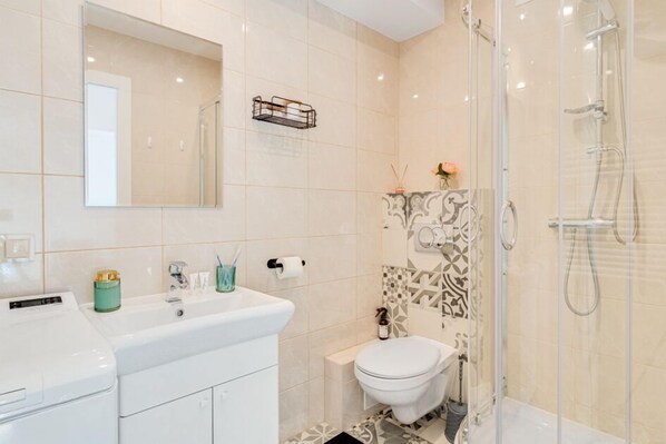 A modern bathroom with a white sink, toilet, and shower. - Apartament na Szewskiej (Wroclaw)