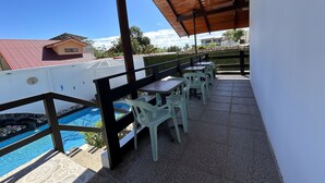 Un espace extérieur abrité, aménagé avec une piscine, des tables et des chaises.