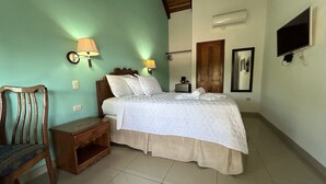 Une chambre à coucher comprenant un lit, une table de chevet, une chaise et un téléviseur fixé au mur.