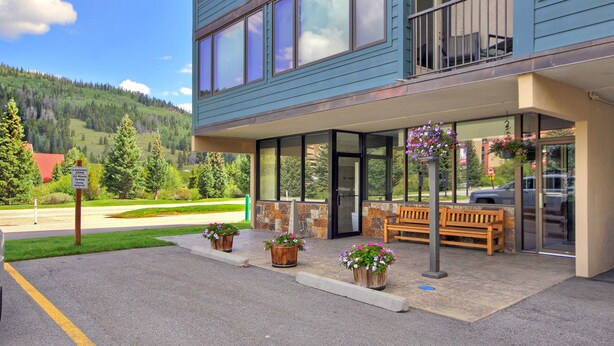 A hotel with a covered entrance, outdoor seating, and a view of a mountainous landscape. - Spacious Condo, Short Walk to Lifts. SH301 (Copper Mountain)