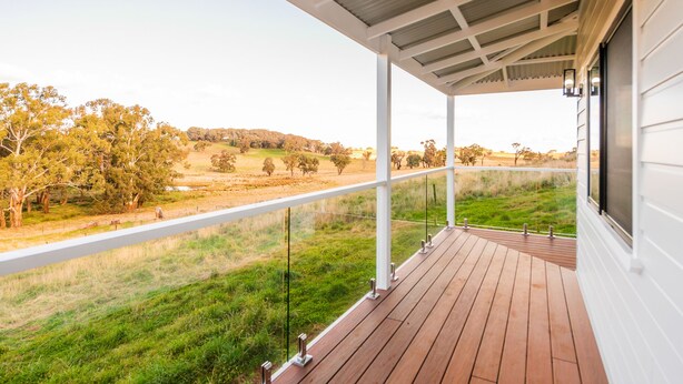 A wooden deck with glass railings overlooking a grassy field and trees. - Off grid luxury space in Central West NSW (Forest Reefs)