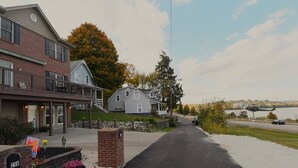 A residential street with houses, a driveway, and a body of water in the background.