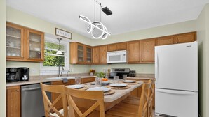 A kitchen with wooden cabinets, a white refrigerator, a microwave, and a dining table set with plates and a vase of flowers.