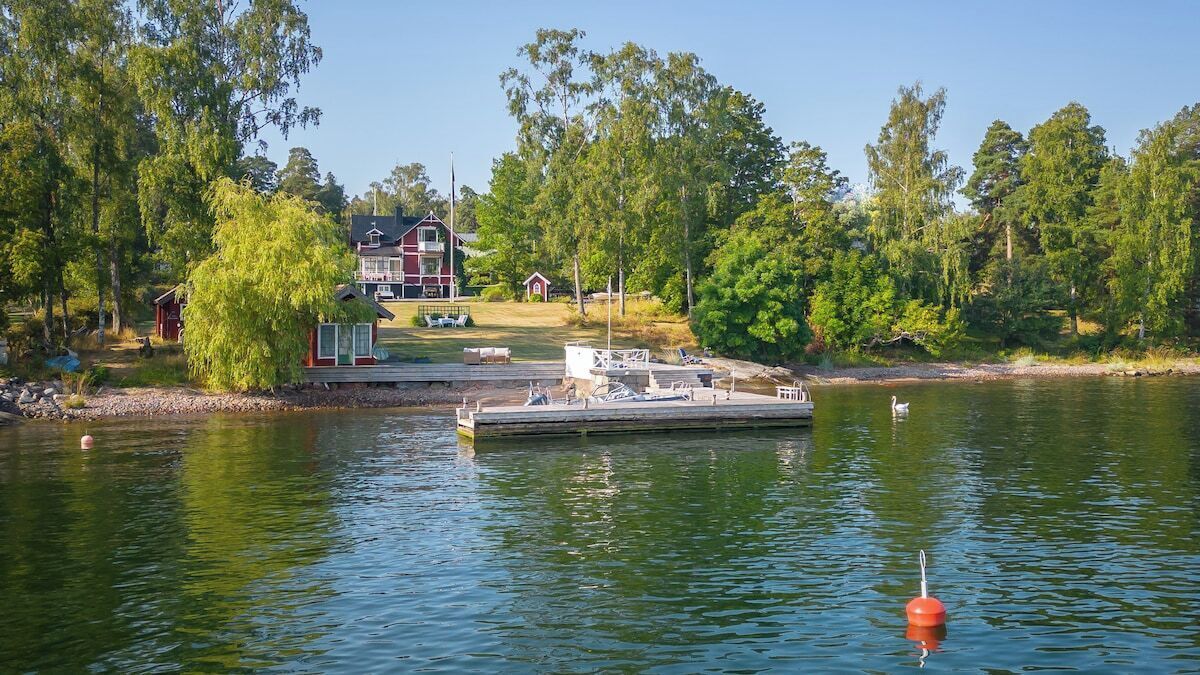 A dock with a boat, a small shed, and a house in the background.