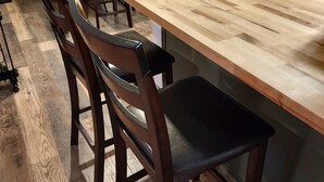 Ein Essbereich mit Holztisch und Stühlen, einer Lampe und einem Kühlschrank.