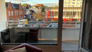 En balkong med utsikt över en stadsbild, inklusive byggnader och en flagga.