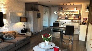 Ett modernt vardagsrum med en soffa, ett soffbord med en vas med blommor och en matplats med ett bord och stolar.