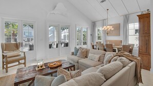 Ein geräumiges Wohnzimmer mit einem großen Sofa, einem Holztisch und einem Essbereich mit Tisch und Stühlen.