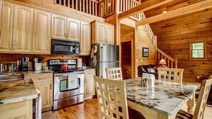 Cocina de cabaña de madera con comedor, que incluye estufa, refrigerador y armarios de madera.