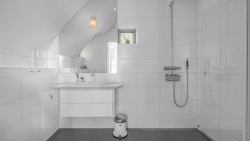 A modern bathroom with a white tiled shower, a sink, and a toilet.