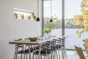 Ein Essbereich mit großem Fenster und Seeblick, einem Holztisch und mehreren Stühlen.