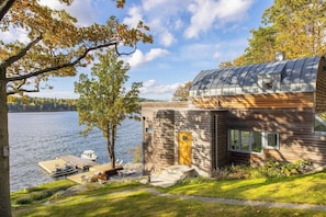 Un chalet au bord du lac, doté d’un quai, d’un bateau et d’une façade en bois.