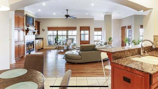 A spacious living room with a fireplace, a dining area, and a kitchen with granite countertops.