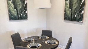 A dining area with a round table, four chairs, and two wall-mounted paintings.