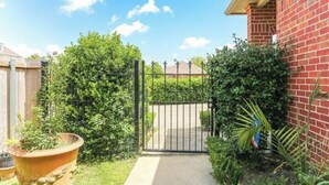 A gated backyard with a brick wall, a wooden fence, and a large potted plant.