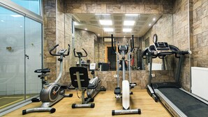 Uma academia com diversos equipamentos de exercício, incluindo esteiras, bicicletas ergométricas e um remo.