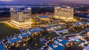 A large, modern hotel complex with multiple high-rise buildings, extensive outdoor swimming areas, and well-lit pathways. - Redefining luxury one click at a time (Ho Chi Minh City)