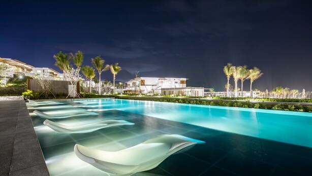 A swimming pool with clear water, surrounded by palm trees and modern buildings. - Redefining luxury one click at a time (Ho Chi Minh City)