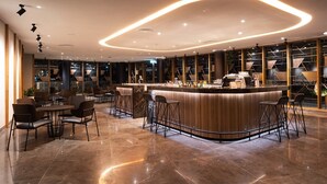A modern bar area with a curved counter, bar stools, and a seating area with tables and chairs. - Redefining luxury one click at a time (Ho Chi Minh City)