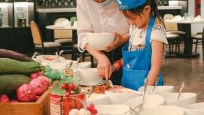 A restaurant setting with a buffet table, various dishes, and a person serving food to another individual. - Redefining luxury one click at a time (Ho Chi Minh City)