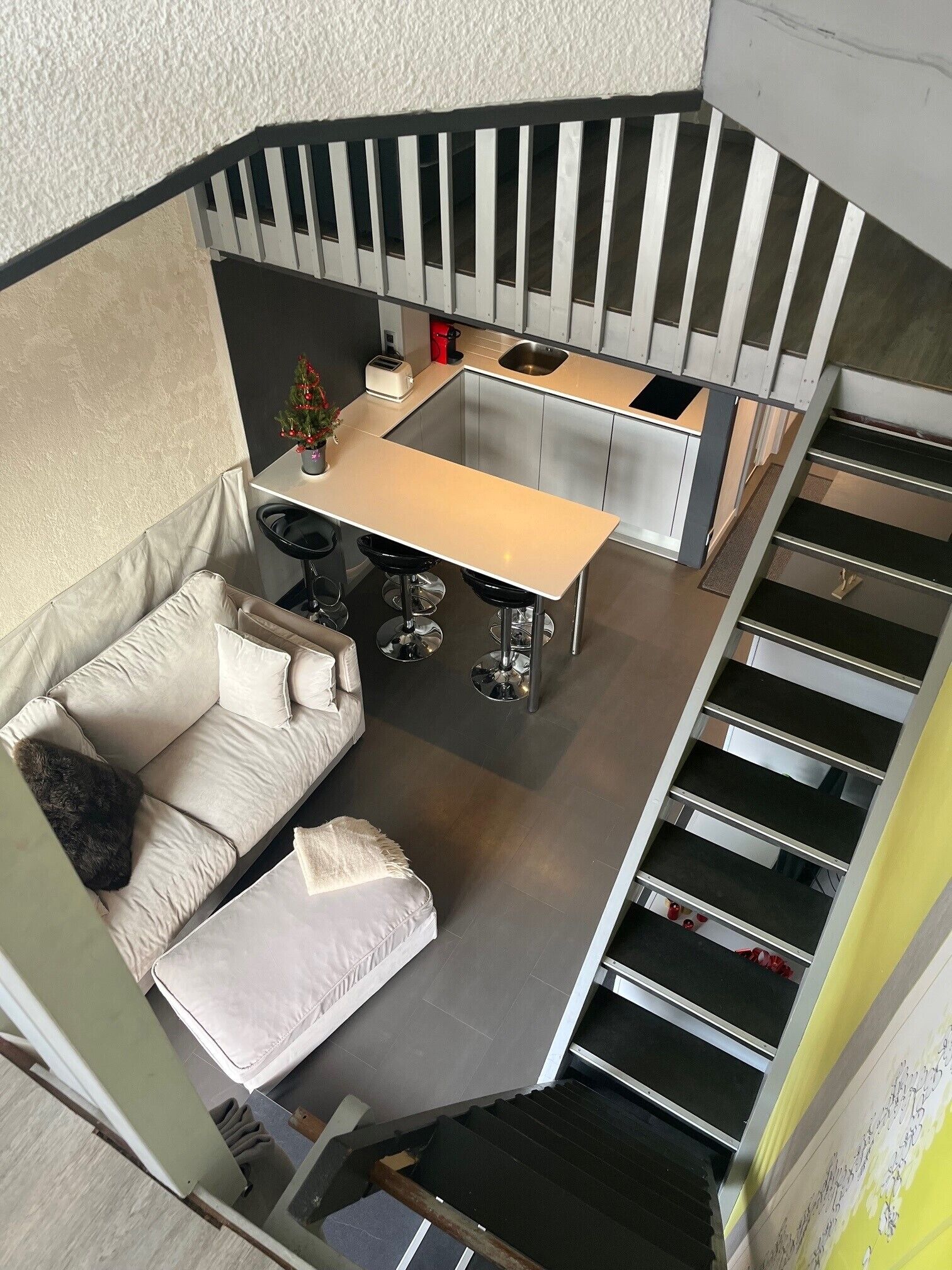 Un espace de vie compact comprenant une kitchenette, un canapé et un escalier.
