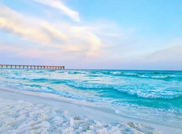 Enjoy a serene beach experience with a picturesque pier stretching into the ocean.