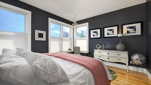 Un dormitorio con una cama grande, un aparador y una araña.