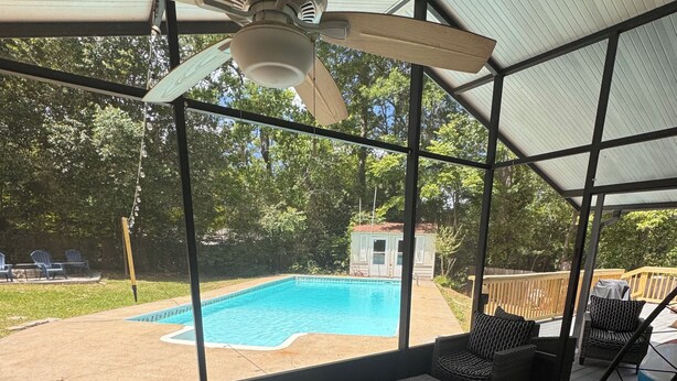 A covered outdoor area with a ceiling fan, a pool, and outdoor furniture. - Work Crew Friendly Housing (Tallahassee)
