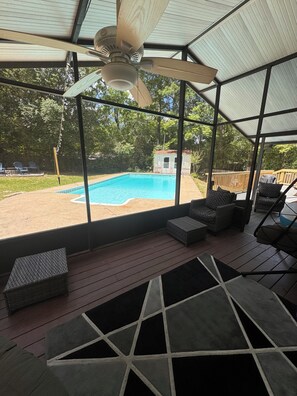 Ett takförsett utomhusområde med en takfläkt, en pool och utomhusmöbler.