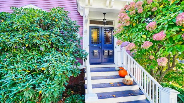 A house with a blue front door, white porch steps, and a small porch area.