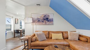 A modern living room with a brown leather sofa, a wooden coffee table, and a painting on the wall.