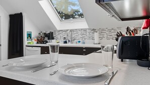 A modern kitchen with a skylight, white countertops, and a coffee machine.