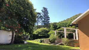 A well-maintained garden with a pergola, a stone wall, and a grassy lawn.