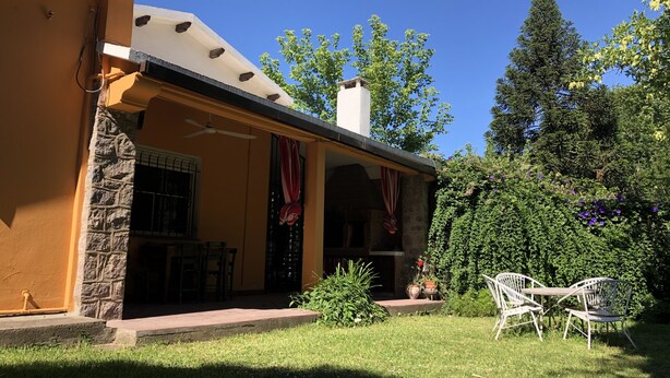 A house with a covered patio, stone walls, a chimney, and outdoor furniture.
